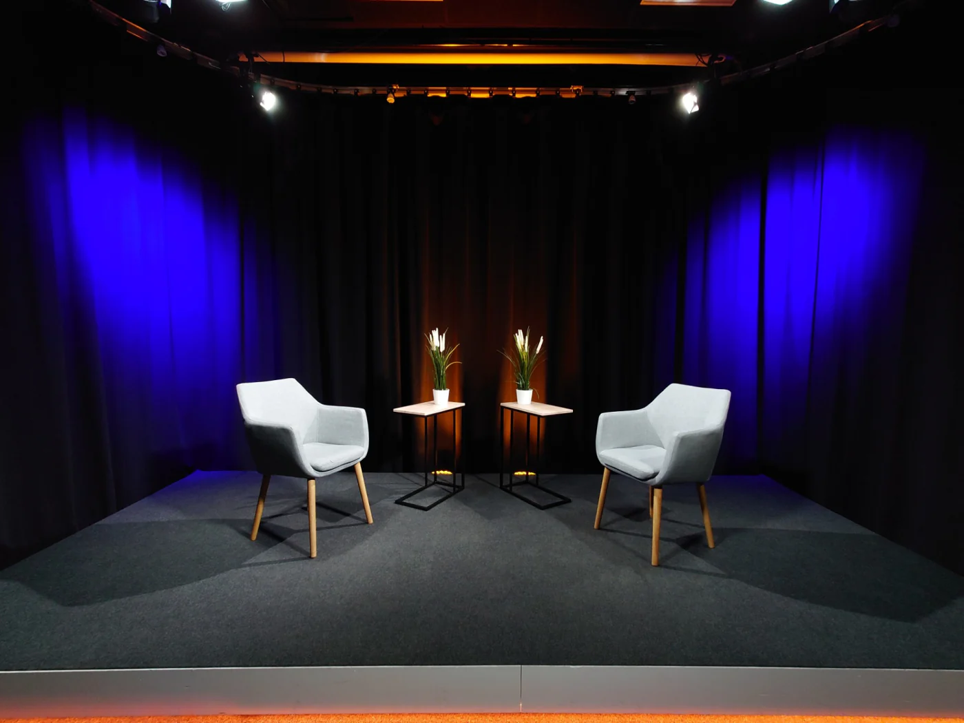 The Eedu video studio, two armchairs on a set stage against a blue-lit backdrop